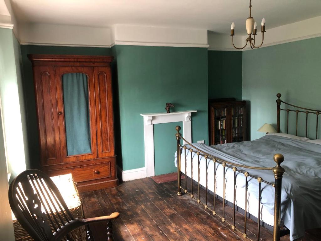 布里德波特The Victorian House的一间卧室设有绿色的墙壁、一张床和椅子