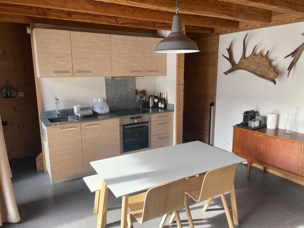 莫尔济讷Chalet Moose的厨房配有白色的桌子和木制橱柜。