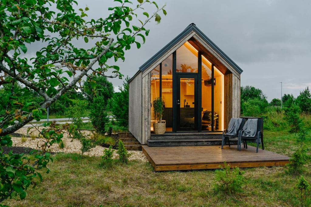 库雷萨雷Unique Tiny House at Saaremaa Golf & Country Club的甲板上的小房子,有长凳