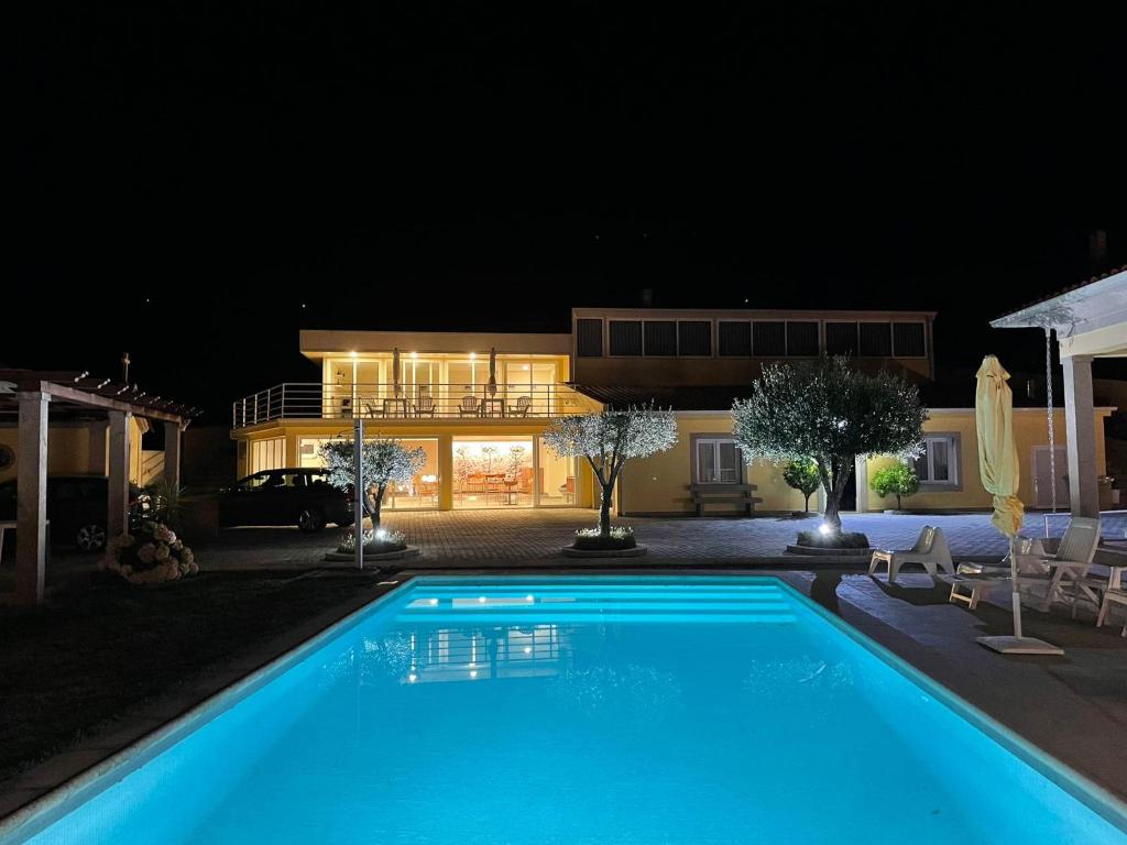 维拉·雷阿尔Quinta da Menina Guest House的夜间在房子前面的游泳池