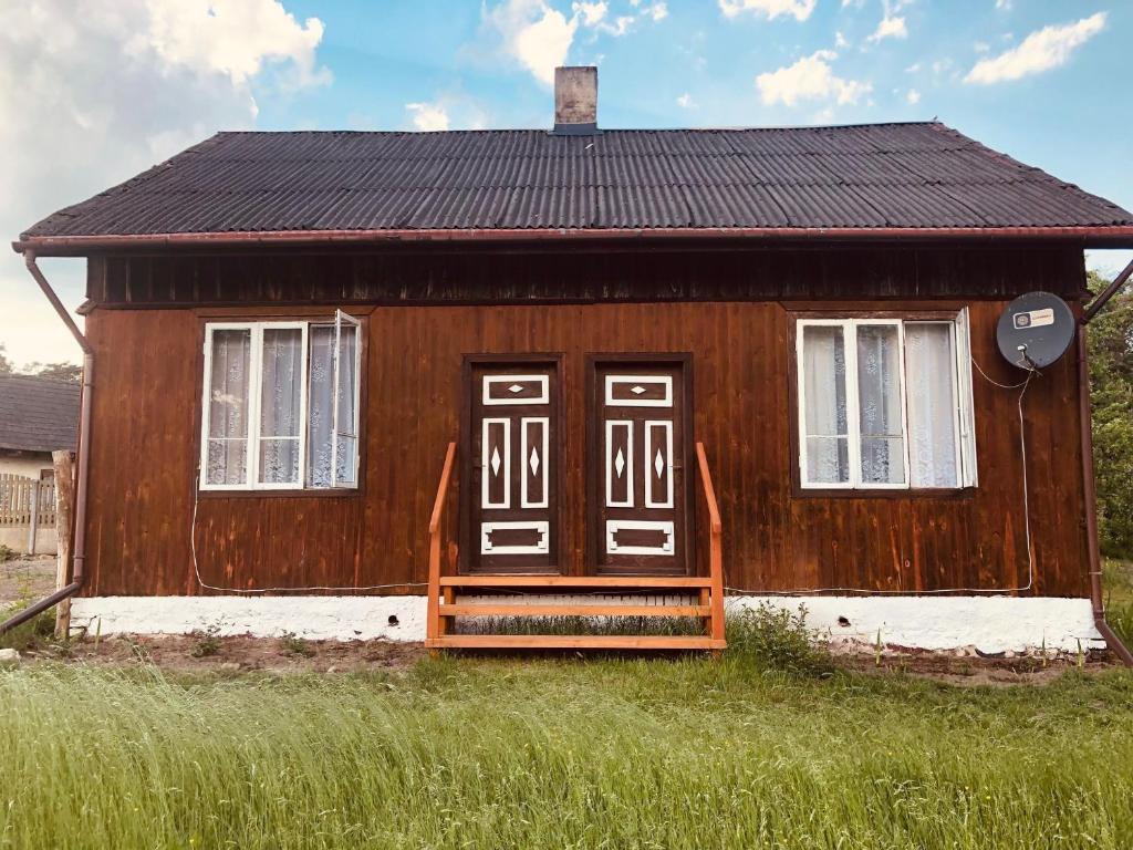 BarkowiceAgroturystyka Mokre的一座小木房子,在草地上设有门廊