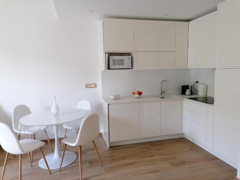 拉帕洛La conchiglia的白色的厨房配有白色的桌子和椅子