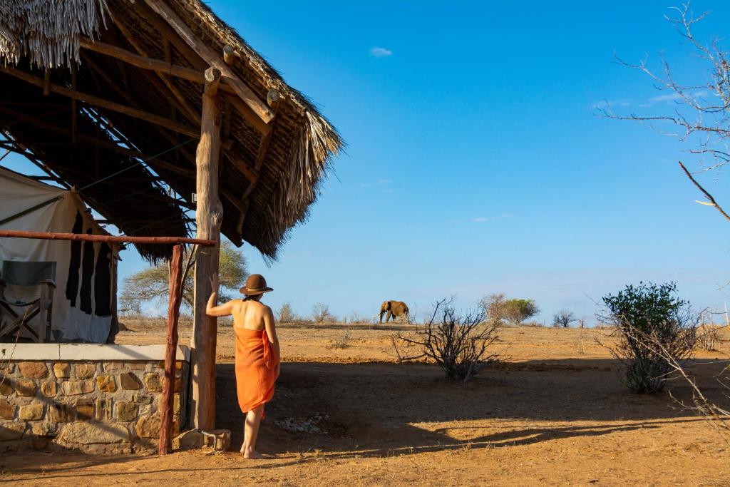 KoitoKudu Safari Camp的身后有骆驼的人站在小屋外