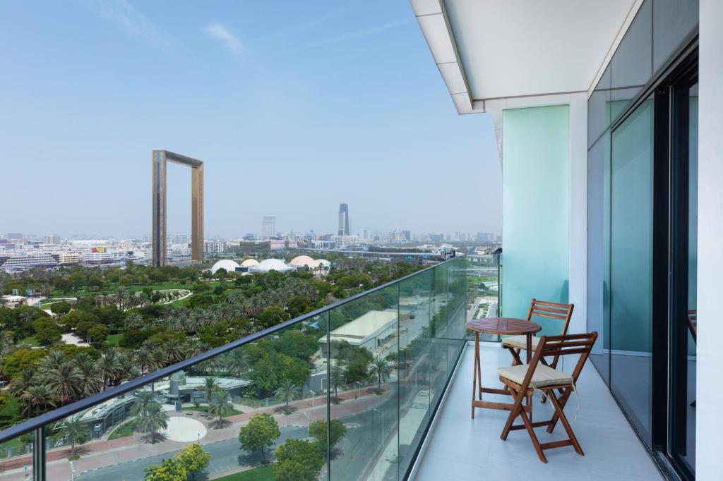 迪拜Maison Privee - Superb 1BR apartment overlooking Zabeel Park and Dubai Frame的阳台配有两把椅子和一张桌子,享有城市美景。