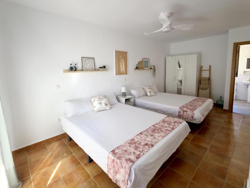 LanzahitaEl Escondite de Gredos的配有白色墙壁和瓷砖地板的客房内的两张床