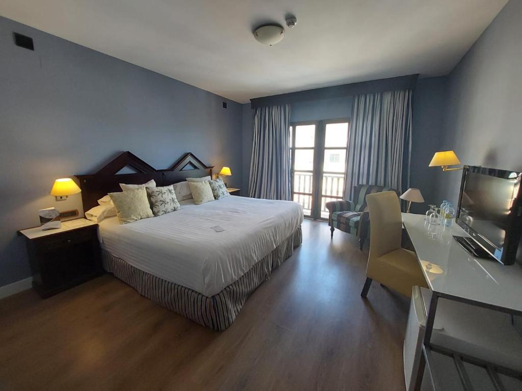 乌贝达RL乌韦达城市酒店的一间卧室配有一张床和一张书桌及电视