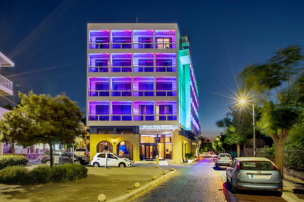 科斯镇亚历山德拉酒店的一座高大的建筑,上面有粉红色和紫色的灯光