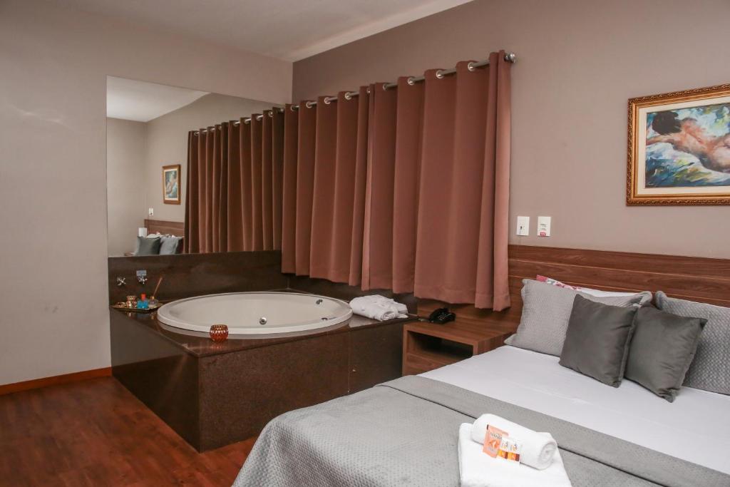 ArcosCAMBRAIA HOTEL ARCOS的一间带浴缸和床的卧室