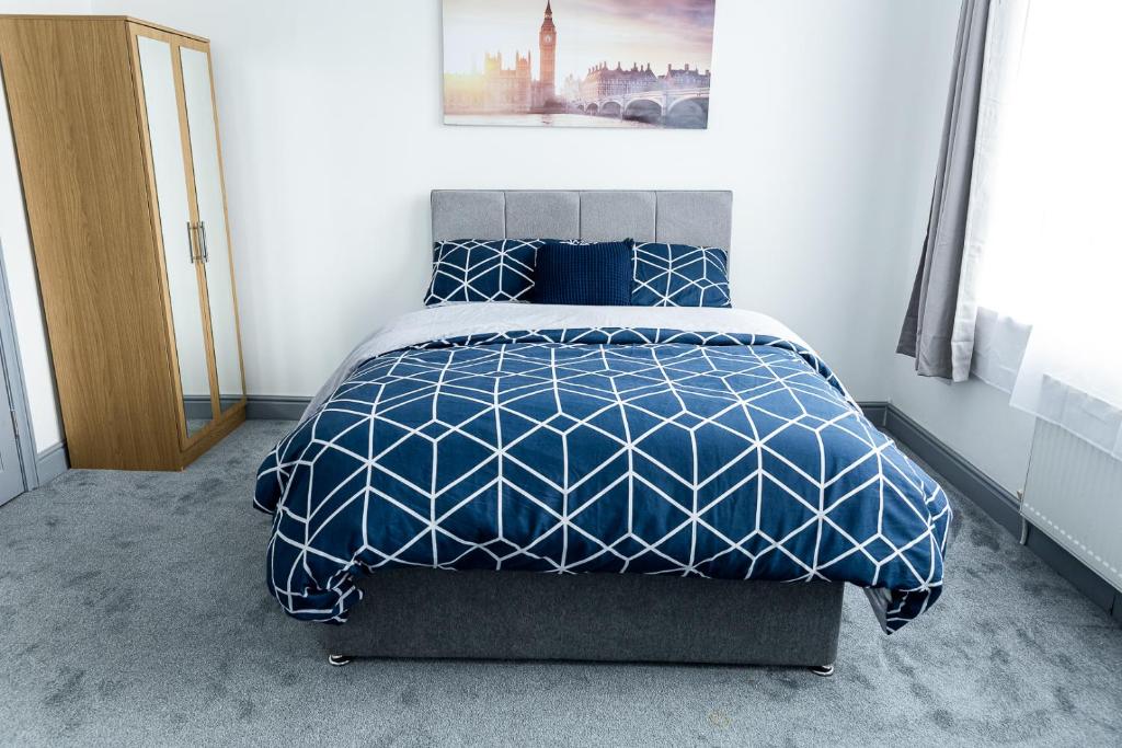 曼彻斯特Empress House的一间卧室配有一张带蓝色和白色棉被的床