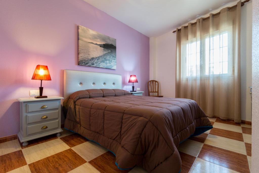 Los Albaricoques阿尔巴乡村酒店的一间卧室设有紫色墙壁和一张带两盏灯的床