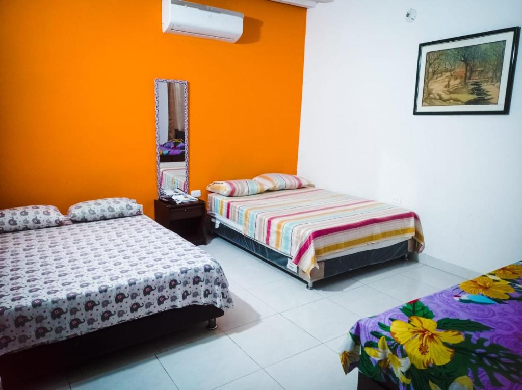 库库塔阿库阿里乌斯酒店的一间卧室设有两张床和橙色的墙壁