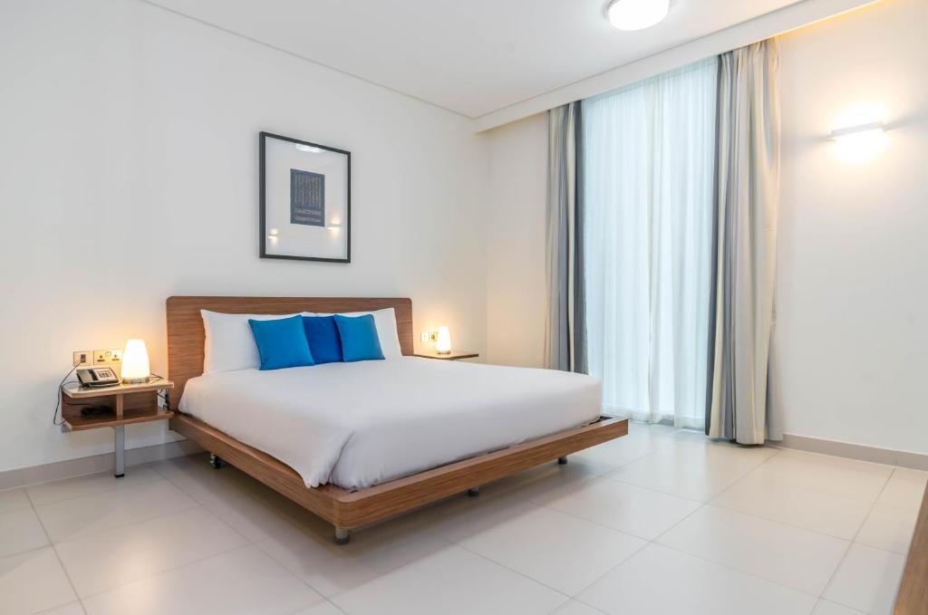 阿布扎比阿达吉奥阿布扎比阿尔布斯坦酒店的一间卧室配有一张带蓝色枕头的大床
