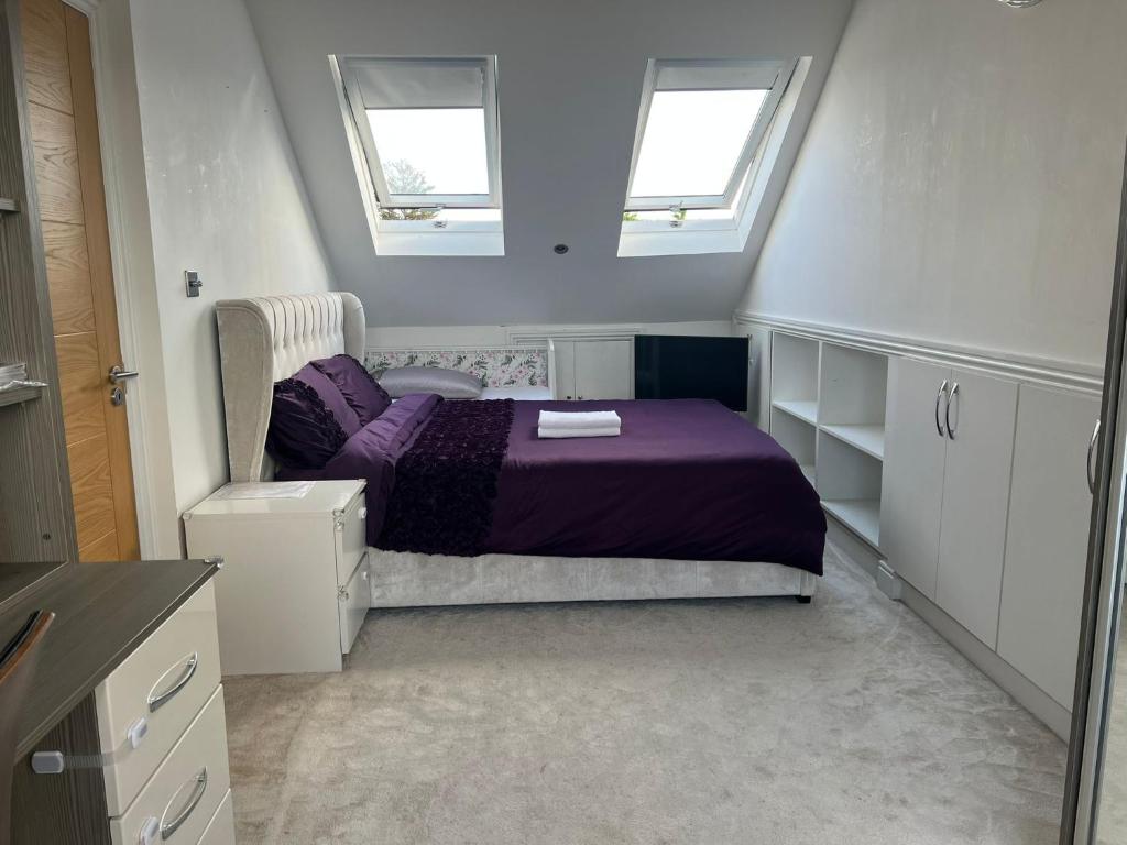 伦敦Deluxe Homestay near Tottenham Hotspur Stadium的一间卧室配有一张紫色的床和两个窗户