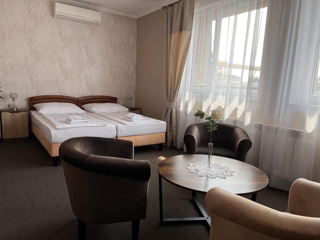 MogilnoNoclegi-Restauracja Boss的酒店客房带两张床和一张桌子以及椅子。