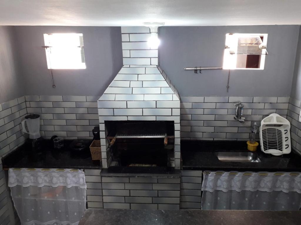 卡波布里奥Casa Super CONFORTÁVEL a 8min da praia do Forte的厨房设有砖砌壁炉和水槽。