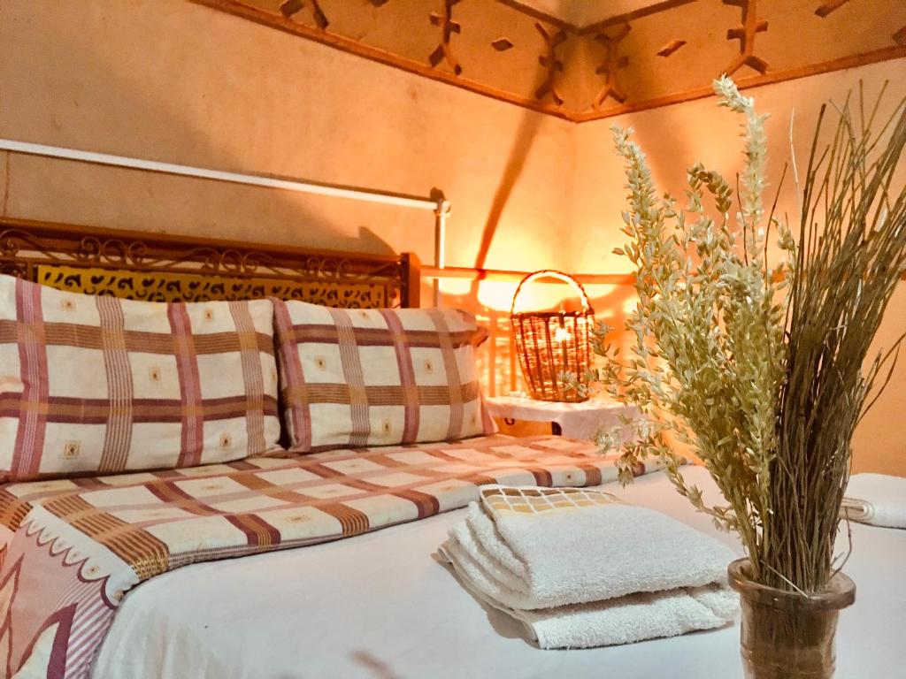 Aït IdaïrHôtel panoramique de la vallée的一间卧室配有床和带毛巾的花瓶。