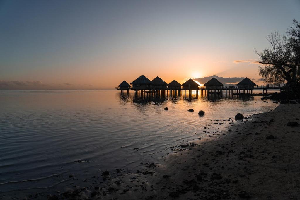 普纳奥亚Le Charme Polynésien proximité plage et commerces的日落时分在水面上建一套小屋
