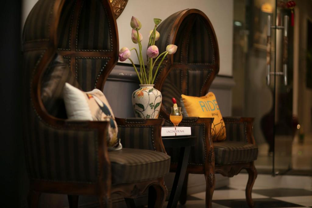 河内Hanoi Garden Hotel & Spa的两张椅子和一个带花卉的花瓶