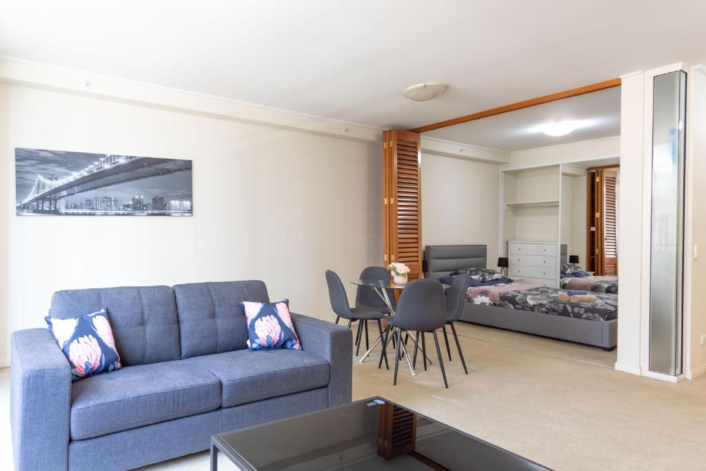 悉尼KULA North Sydney-Napier的一间带蓝色沙发的客厅和一间卧室