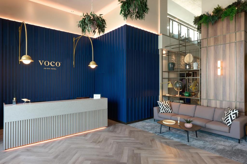 梅斯特voco Venice Mestre - The Quid, an IHG Hotel的一个带沙发和蓝色墙壁的大堂