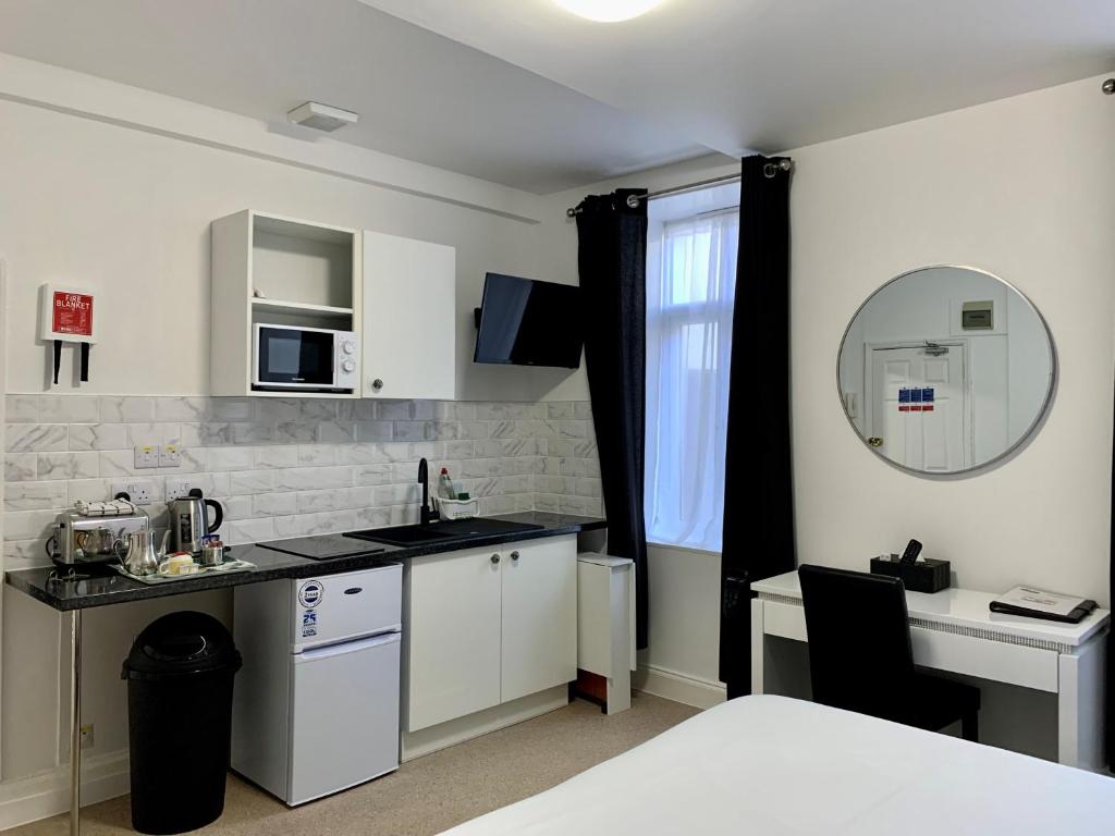 圣赫利尔泽西Sarum Apart-Hotel的厨房配有白色橱柜、水槽和桌子