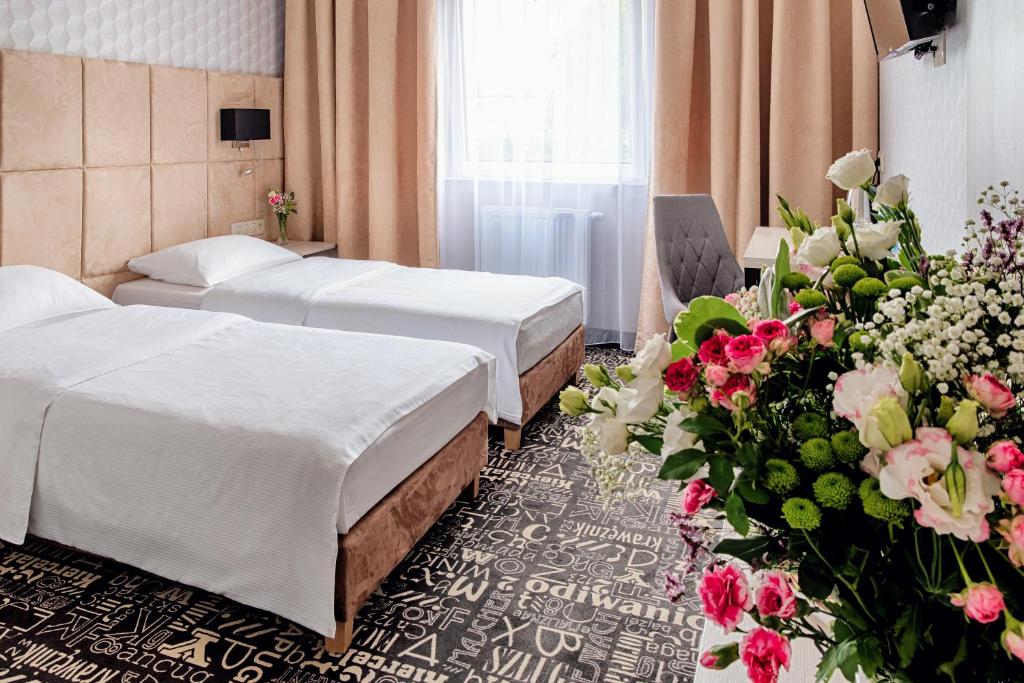 拉辛Citi Hotel's Warszawa-Falenty的酒店客房设有两张床和一束鲜花