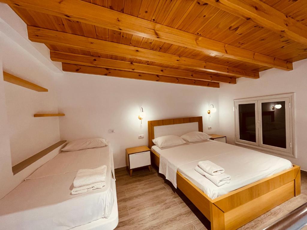 伏罗拉Vila Anxhelo的一间卧室设有两张床和木制天花板