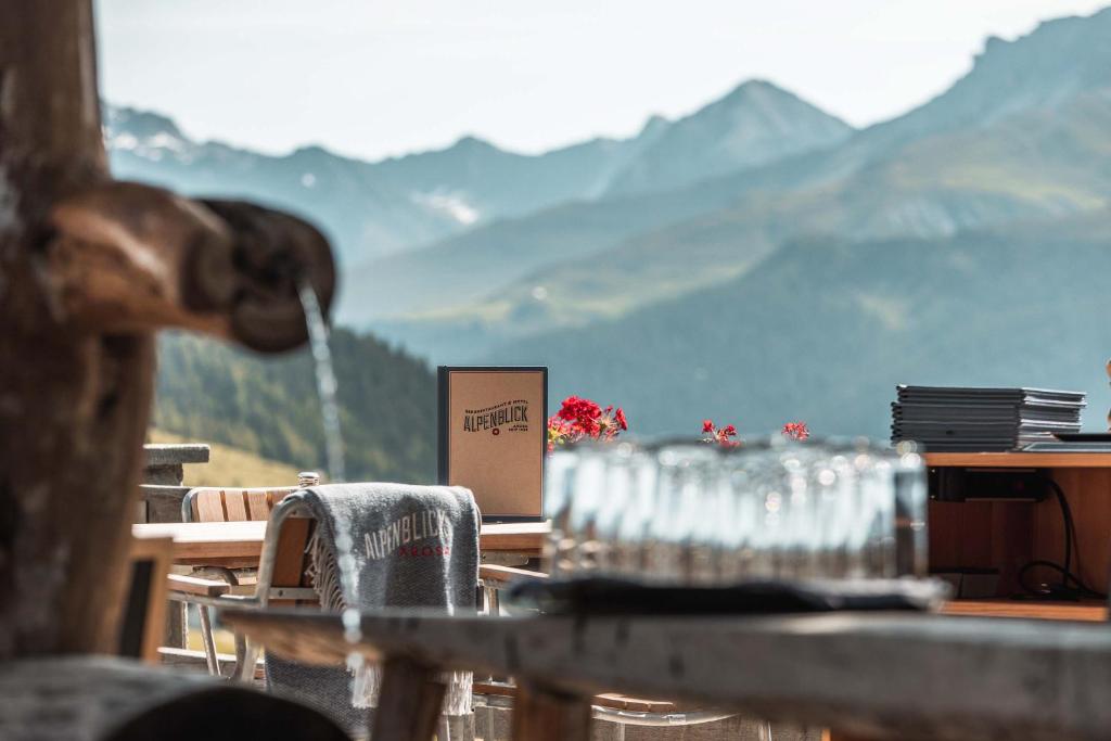 阿罗萨Alpenblick Bergrestaurant & Hotel的一张桌子,上面有眼镜,后面有山