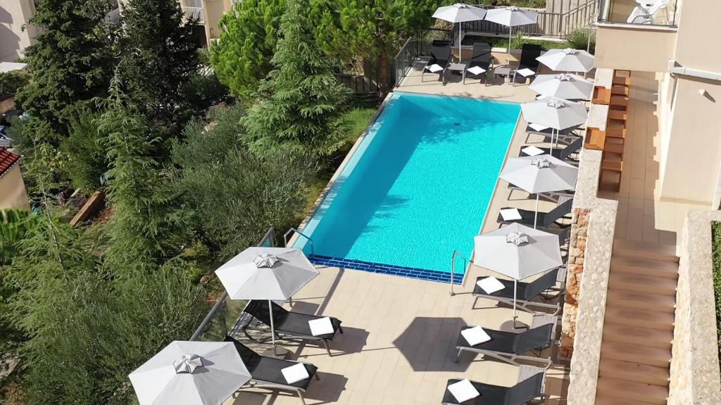杜布罗夫尼克亚德里亚酒店的享有带椅子和遮阳伞的游泳池的上方景色