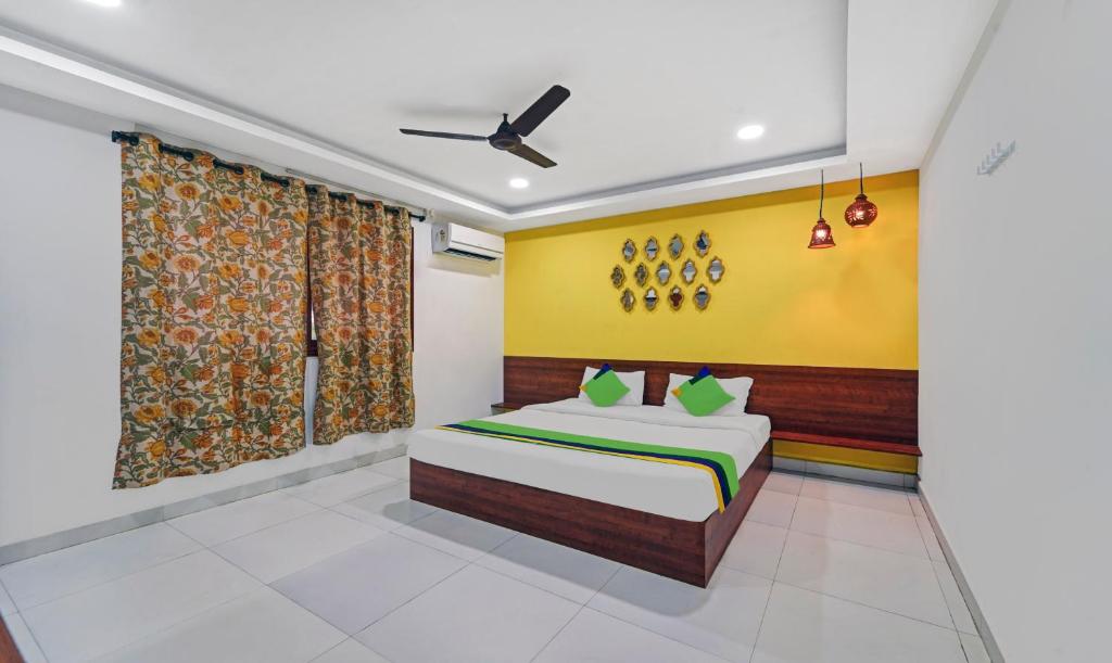 蓬蒂切里Treebo Trend Signature Grande的一间卧室设有一张床和黄色的墙壁