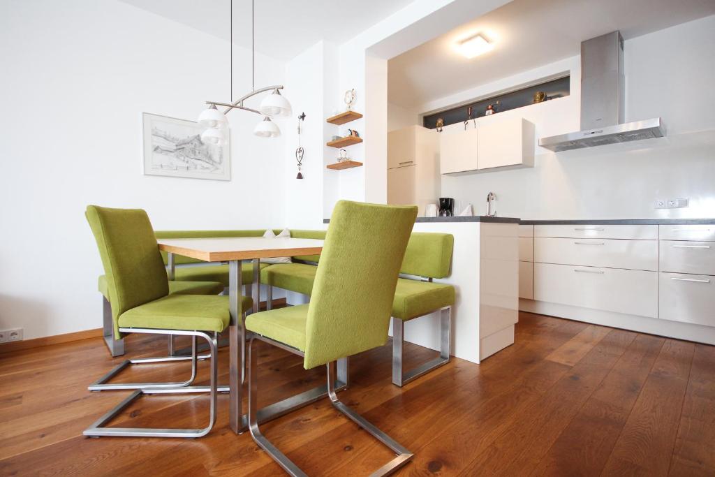 斯拉德明Planai West by Schladming Appartements的厨房配有桌子和绿色椅子