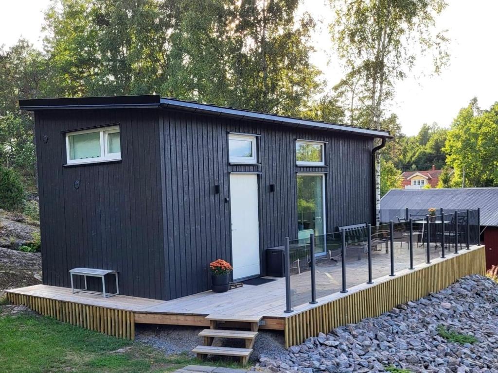 埃斯基尔斯蒂纳Cabin in the woods, close to Lake Mälaren的木制甲板上的一间黑色小房子
