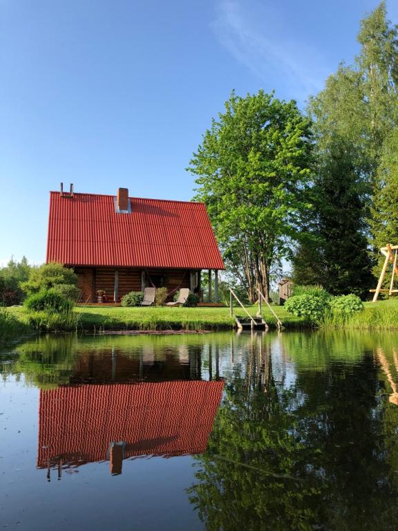 SīveciPirts Baudas的湖边一座红屋顶的房子