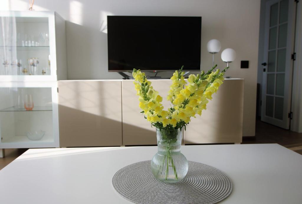 帕兰加BAM apartments的摆在桌子上的花瓶,上面装着黄色的花
