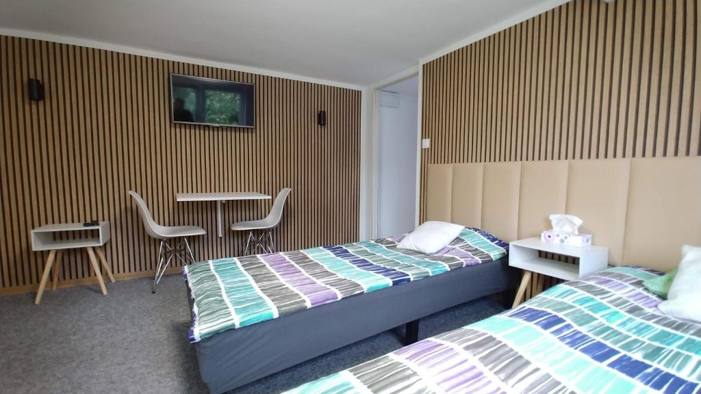 波兹南Noclegi Malta Poznań的一间卧室配有两张床和一张桌子及椅子