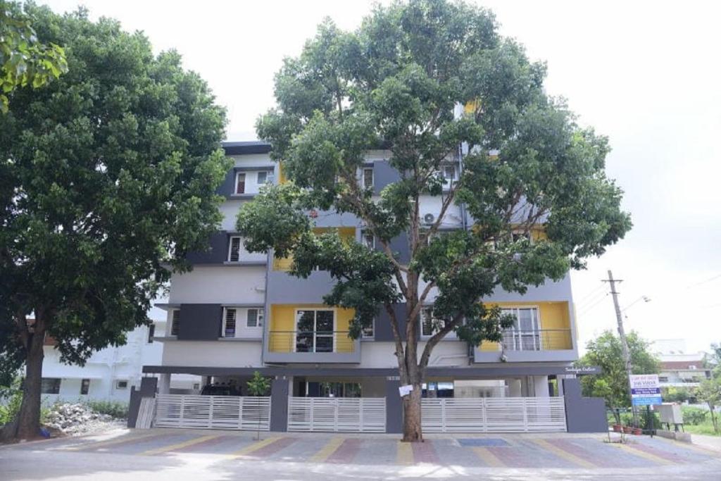 迈索尔The Vihar service Apartment的前面有棵树的建筑