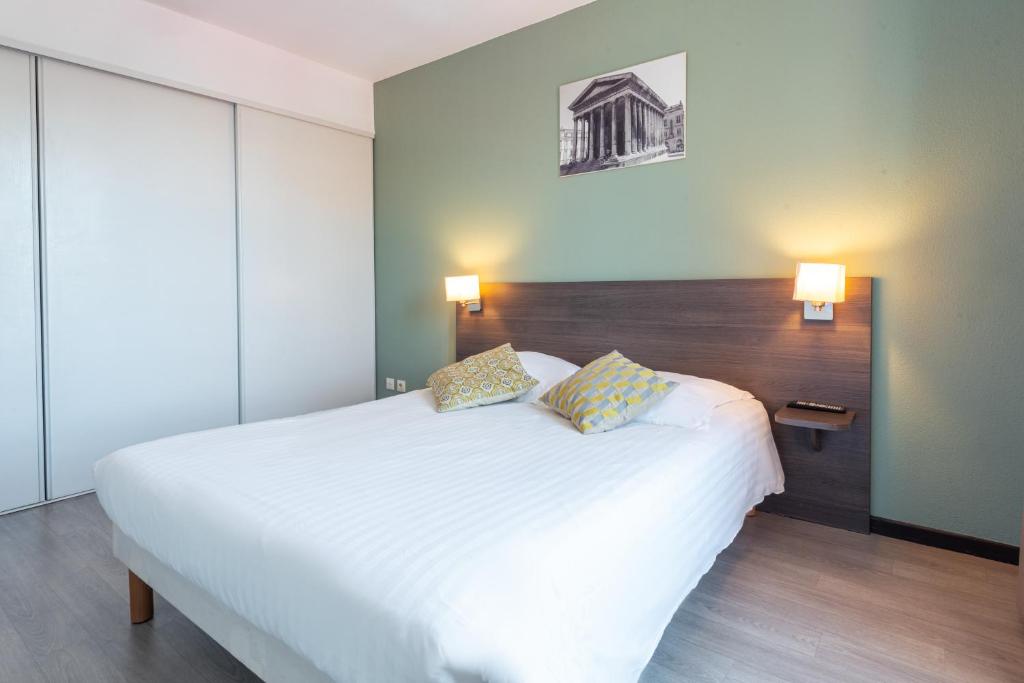 尼姆Zenitude Hôtel-Résidences Nîmes Centre的卧室配有一张带两个枕头的大白色床