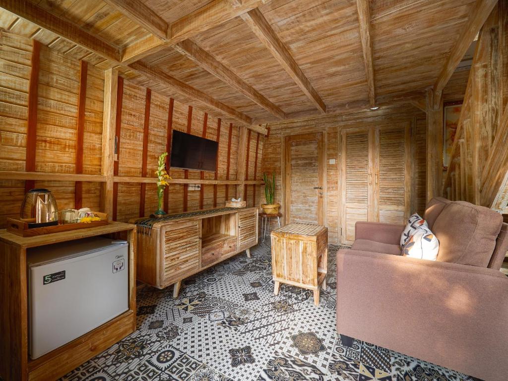 乌鲁瓦图Wisnu Lumbung Uluwatu的小屋内的客厅配有沙发和电视