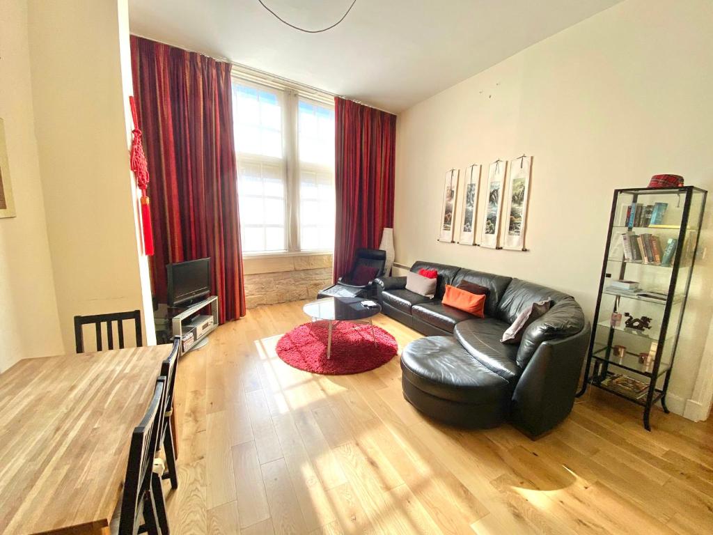 爱丁堡Royal Mile Mansions by Edinburgh City Apartments的客厅配有黑色真皮沙发和桌子