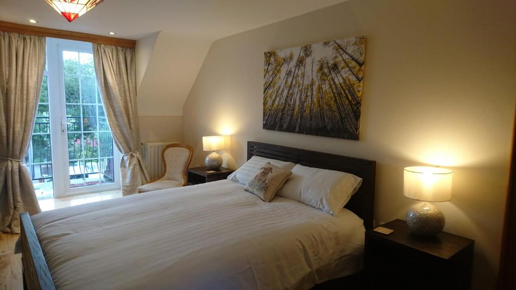 恩尼斯基林Rossclare Lodge的一间卧室配有一张带两盏灯的床和一扇窗户。
