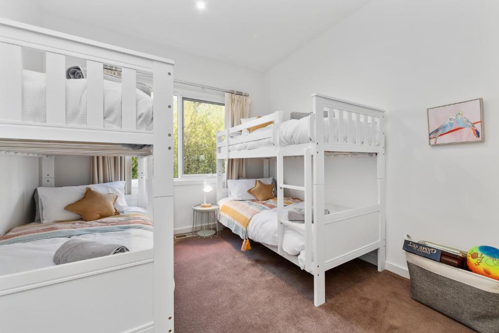 SeafordSeaford Luxe Beach House 2023 BDC Traveller award winner的卧室的客房内配有2张白色双层床