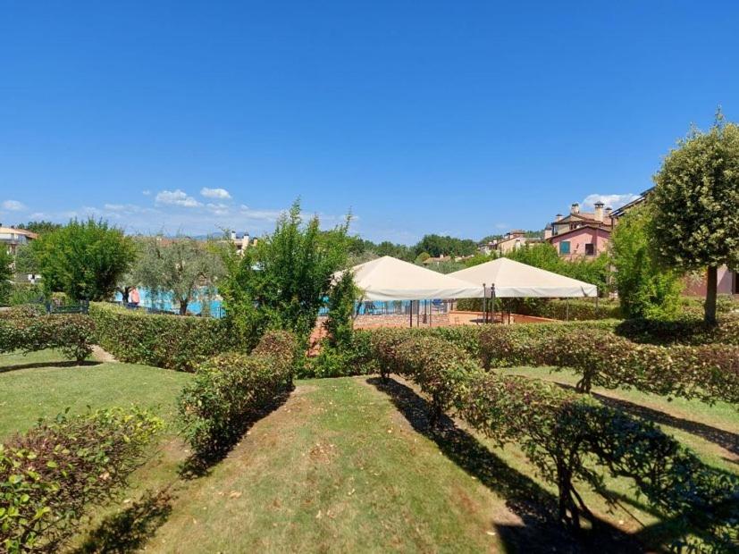 佩斯基耶拉德加达Resort il cigno的一座种植了灌木和树木的花园以及帐篷