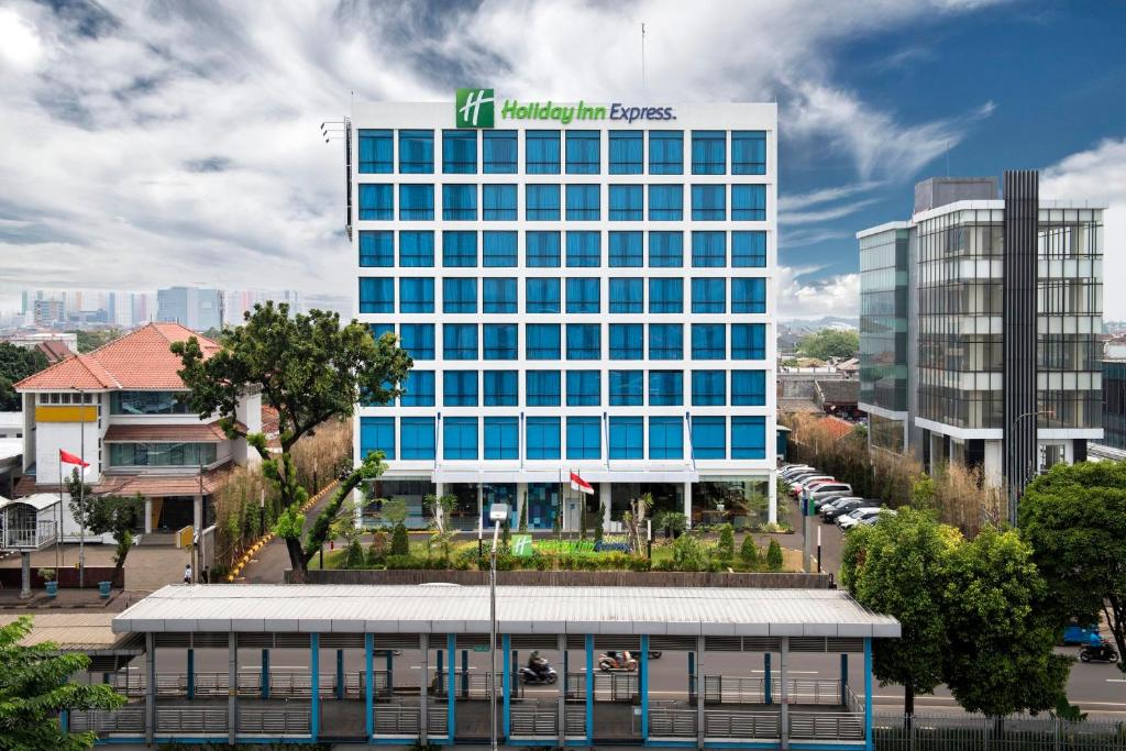 雅加达Holiday Inn Express Jakarta Matraman, an IHG Hotel的一座高大的建筑,上面有标志