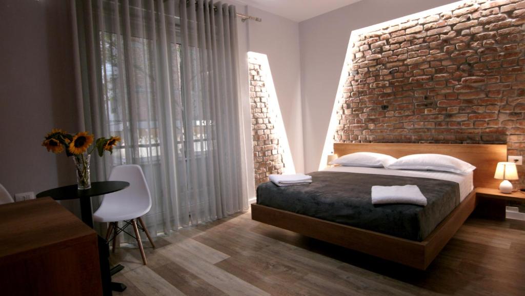 地拉那KONI's Studio Apartments的一间卧室设有砖墙和一张床