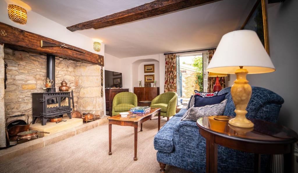 谢伯恩The Sherborne Cottage的客厅设有蓝色的沙发和石制壁炉
