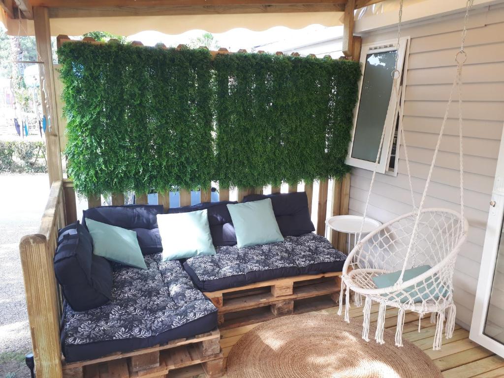 雷日卡普费雷charmant Mobil-home climatisé - Cap ferret的一个带沙发和绿色墙壁的门廊