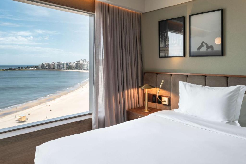 蒙得维的亚Hotel Costanero MGallery - ACCOR的一间卧室配有一张床,享有海滩美景