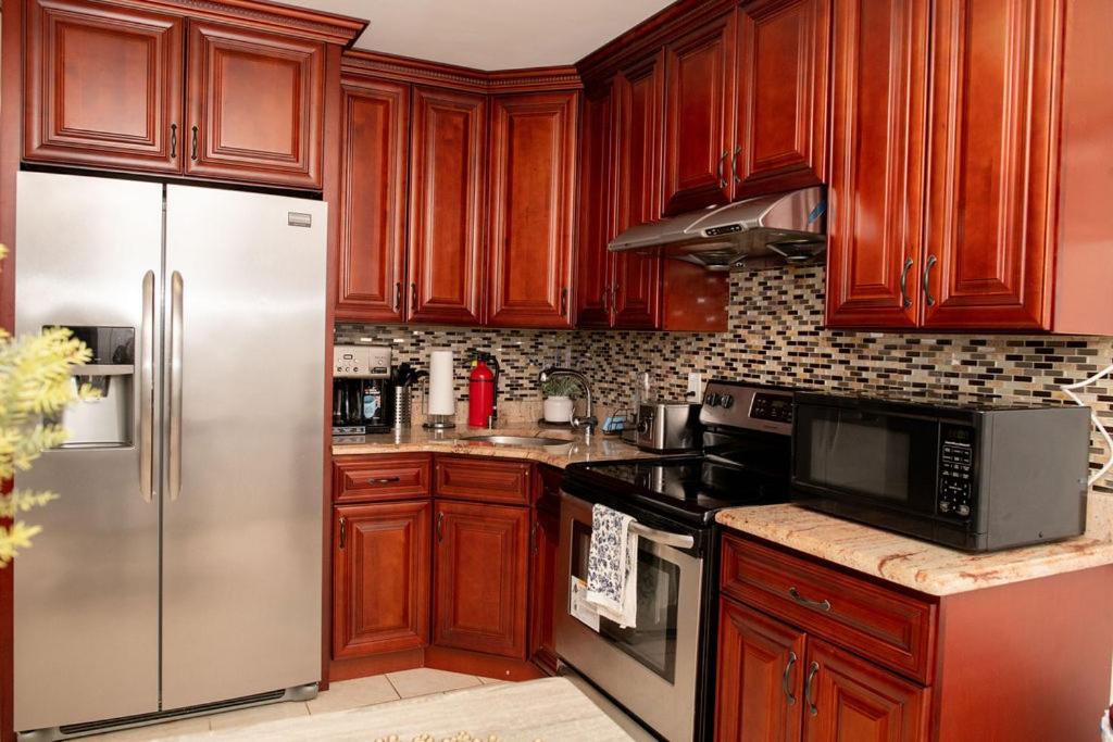 罗斯代尔Tonel Paradise 1BR private entrance Near JFK的厨房配有木制橱柜和不锈钢冰箱。