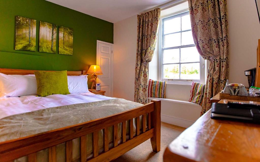 达特茅斯The Ship in Dock Inn的一间卧室设有一张带绿色墙壁和窗户的床。