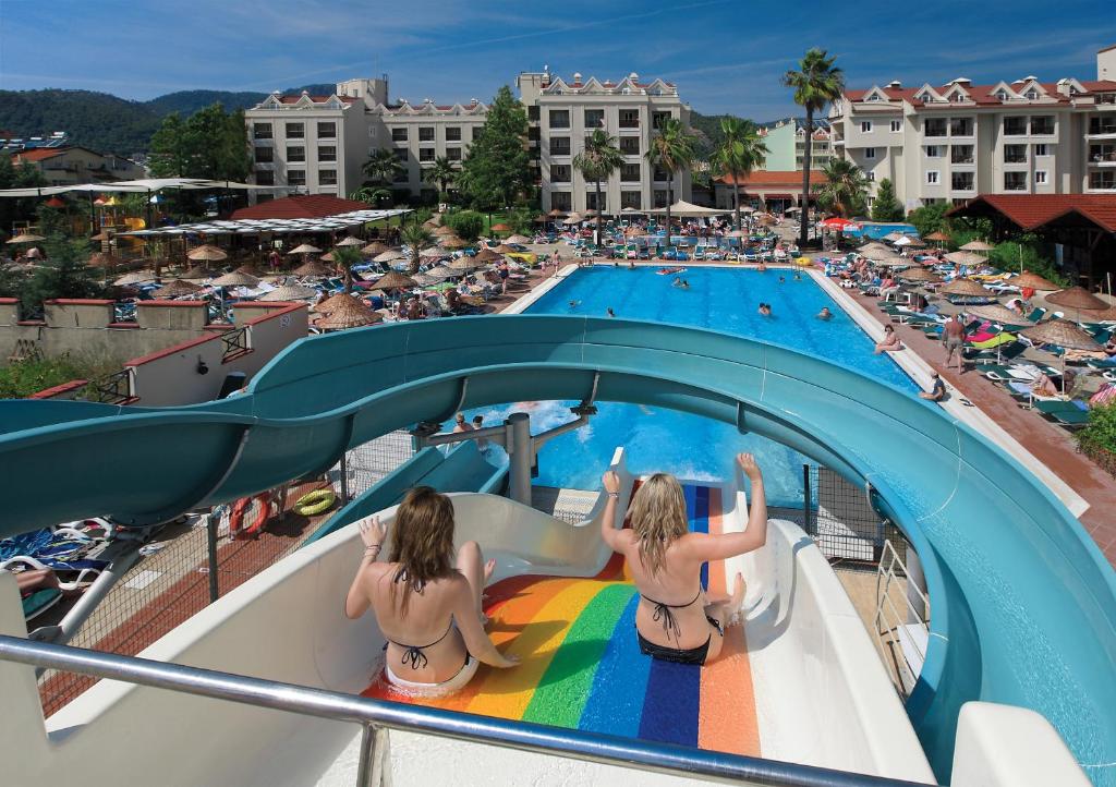 马尔马里斯朱利安俱乐部酒店的两个穿着泳衣的女孩坐在游泳池滑梯上